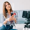 Influenser filmer sminkevideo med mobil og stativ som del av influensermarkedsføring på sosiale medier