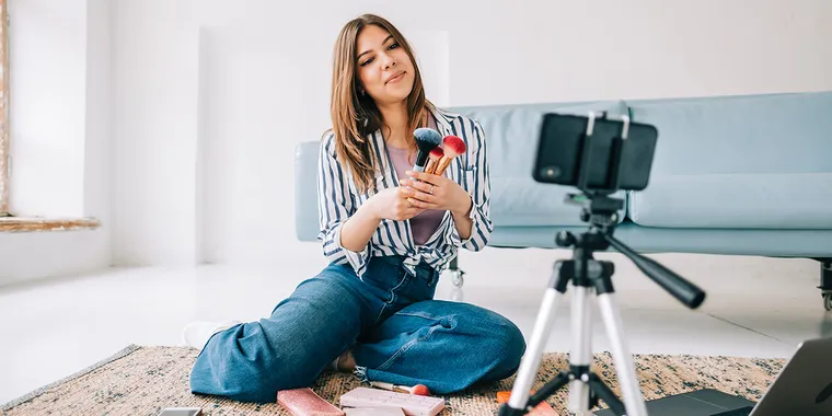 Influencer filming makeup video with phone and tripod as part of influencer marketing on social media
