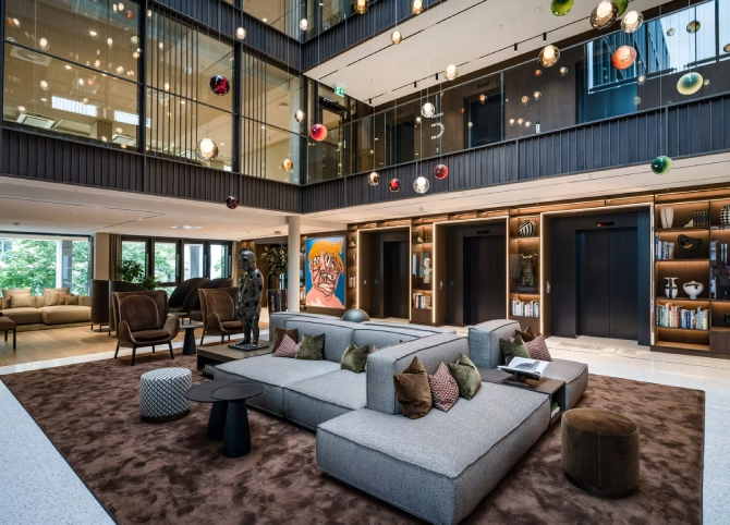 The lobby at The Box in Sannergata 2, with sofa groups, art and colored pendant lamps in a double-height atrium