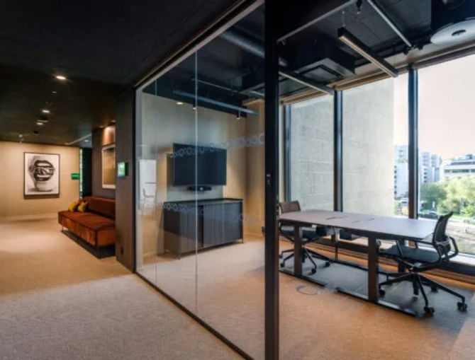 A private office at The Box, Box12 Momentum, with a desk and office chairs behind a glass wall facing large windows