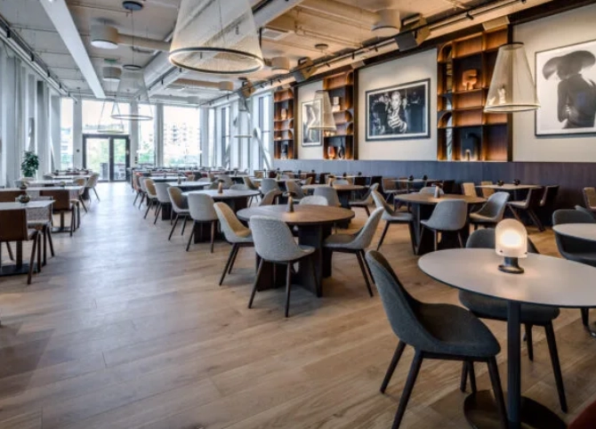 The in-house restaurant at The Box, with tables and chairs in several zones, art on the walls and windows along the whole room